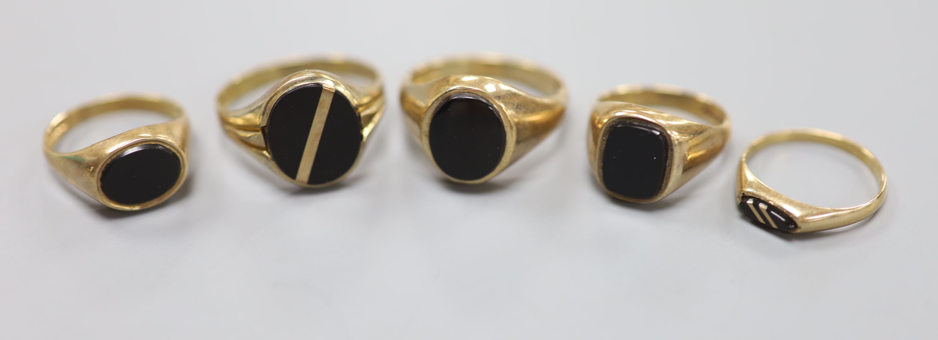 Four assorted modern 9ct gold and black onyx set signet rings and one other similar ring, largest size V/W